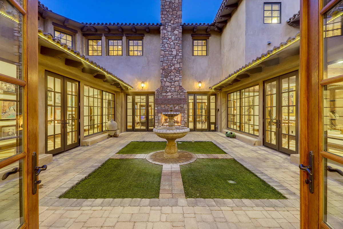 A large square interior courtyard greets visitors as they enter the home. It's park-like settin ...