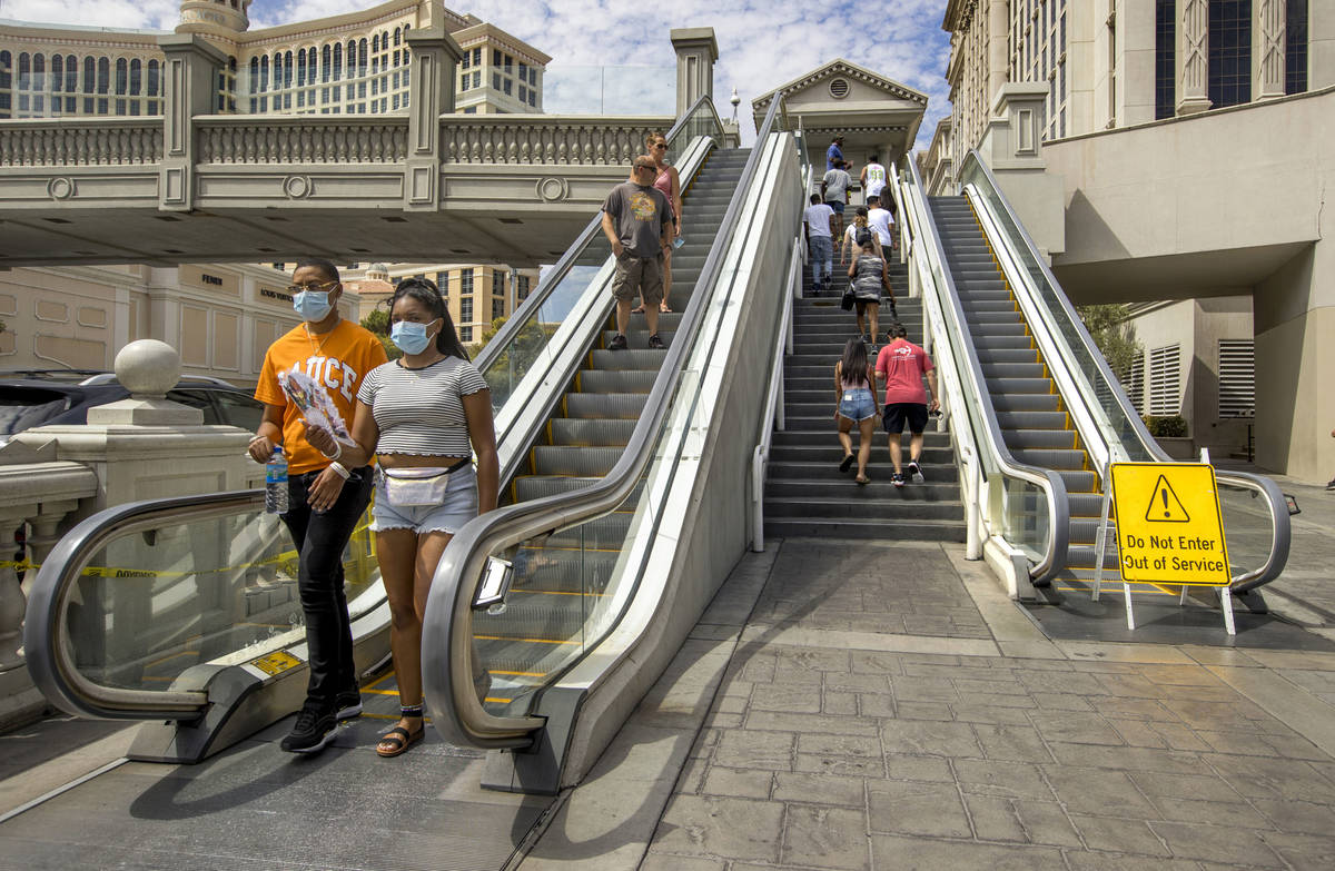 Pedestrians work their way down and up the bridge that crosses East Flamingo Road between Caesa ...