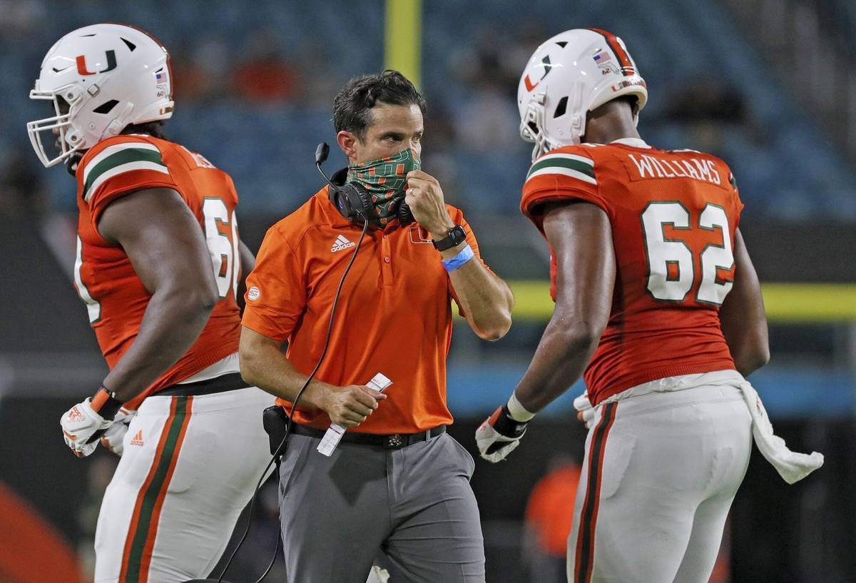 Miami coach Manny Diaz, center, walks on the field during an NCAA college football game against ...