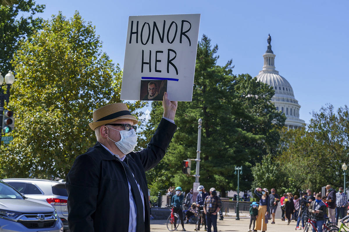A man holds up a sign in honor of the late Justice Ruth Bader Ginsburg, as people gather at the ...