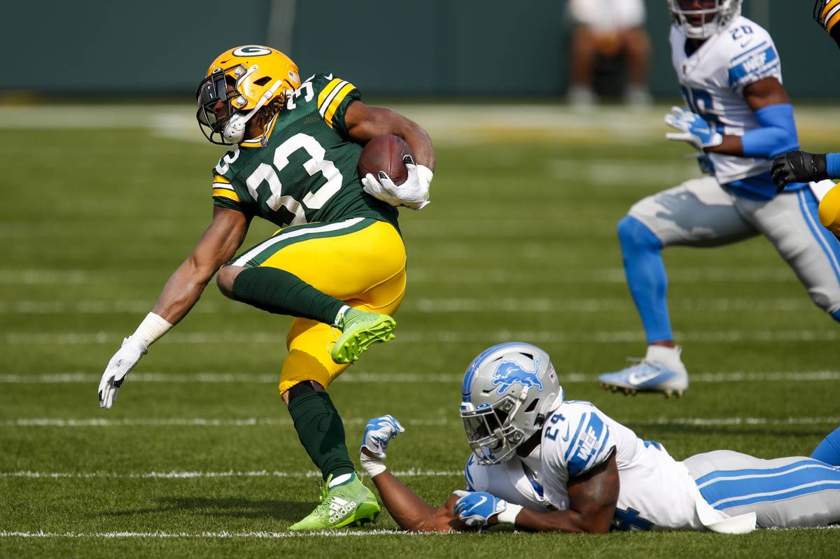 Green Bay Packers' Aaron Jones runs past Detroit Lions' Amani Oruwariye during the first half o ...