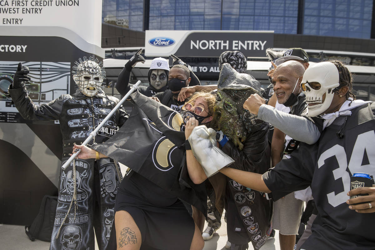 New Orleans Saints fan Amy Laughlin is surrounded by Las Vegas Raiders characters as they gathe ...