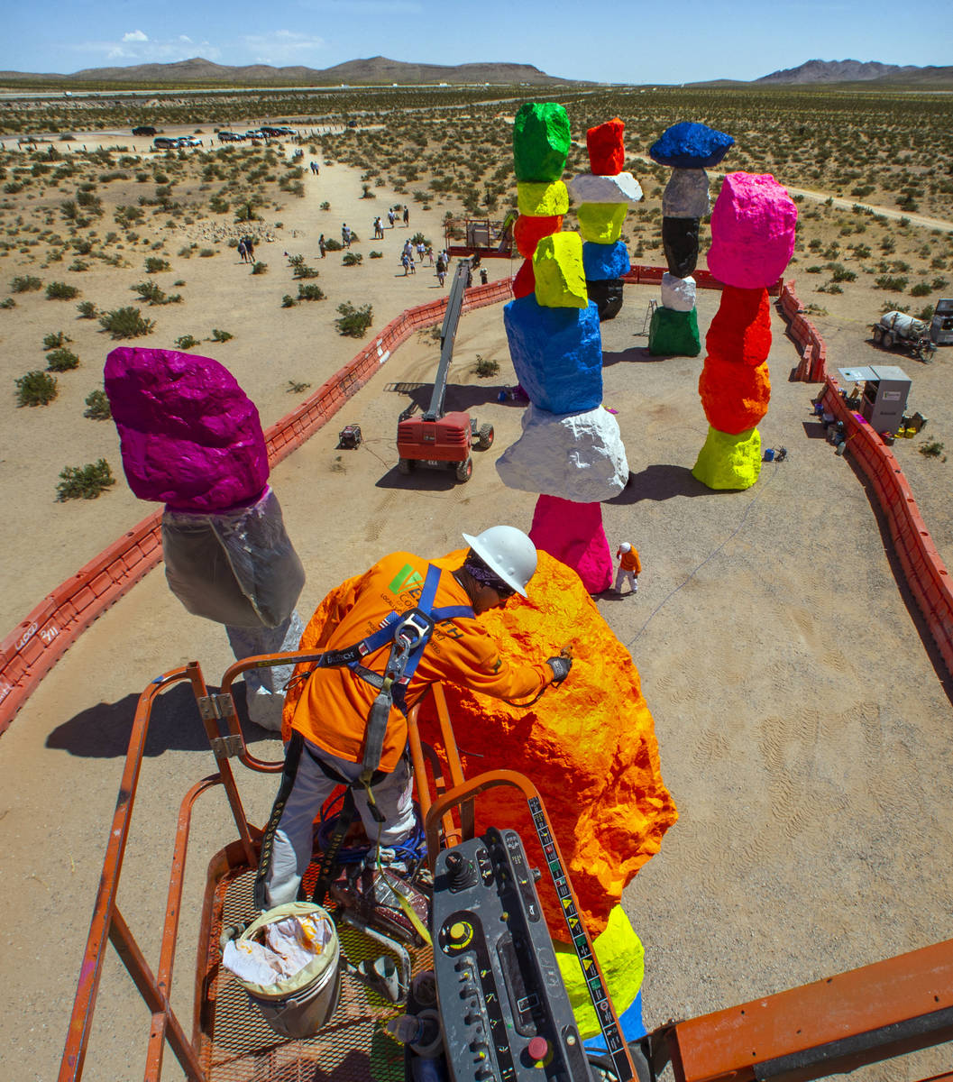 John Henderson sprays a final clear protective coating on the rocks June 18. The art installati ...