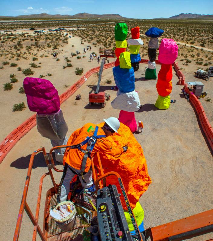 John Henderson sprays a final clear protective coating on the rocks June 18. The art installati ...