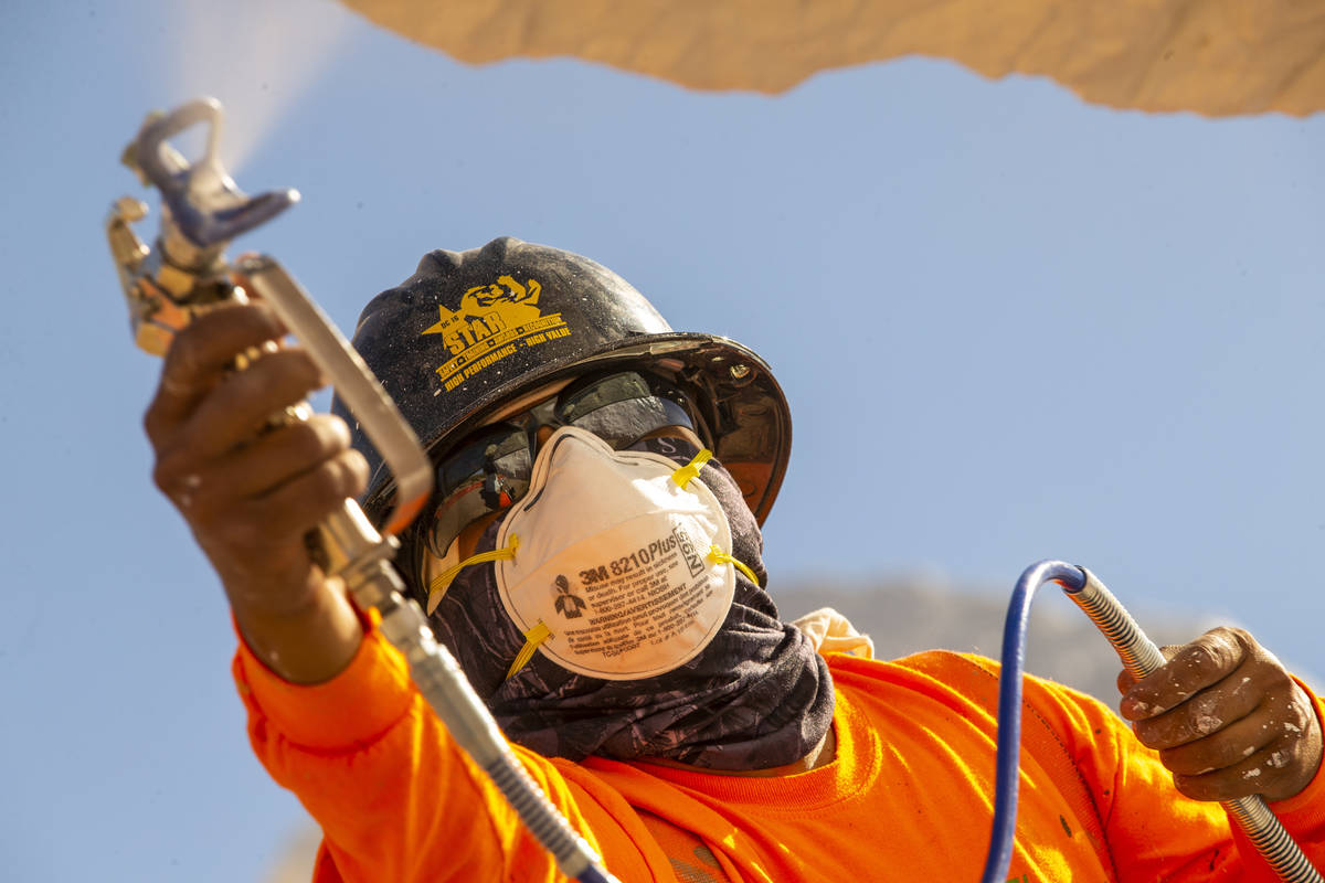 Jose Cervantes with Vergith Contracting Co. evenly sprays a white finish on one of the rocks du ...