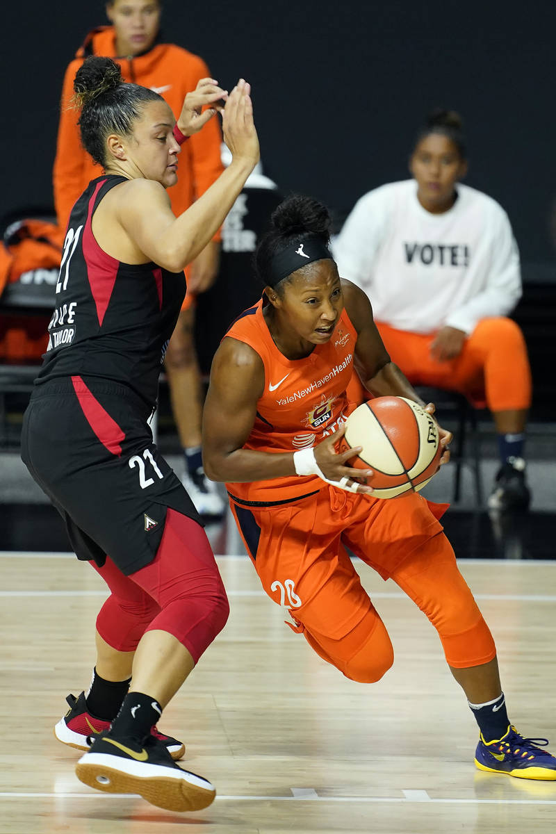 Connecticut Sun guard Briann January (20) drives around Las Vegas Aces guard Kayla McBride (21) ...