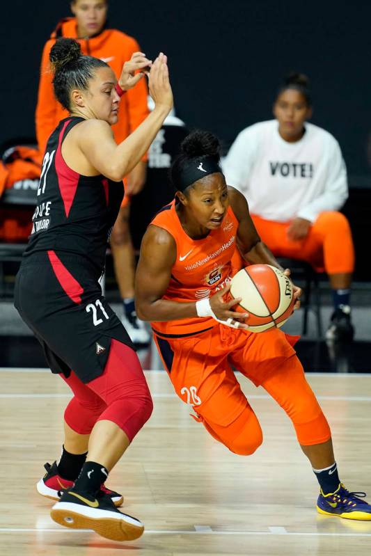 Connecticut Sun guard Briann January (20) drives around Las Vegas Aces guard Kayla McBride (21) ...