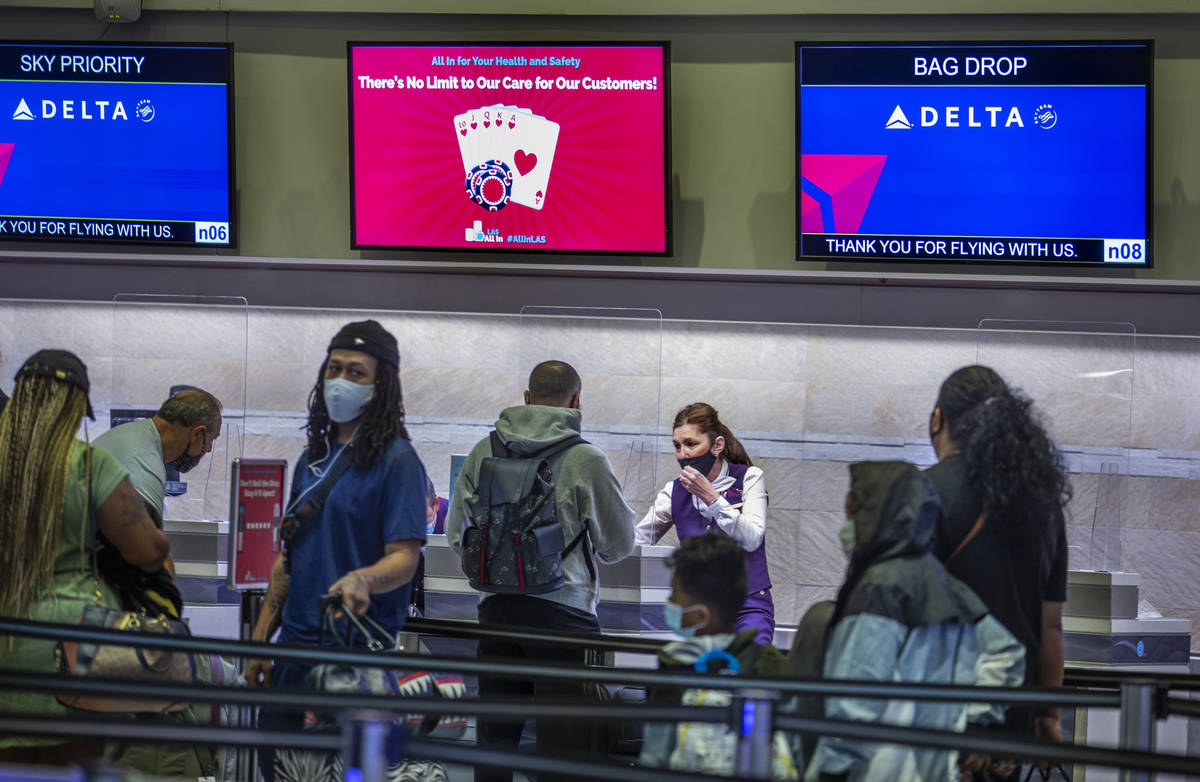 Delta Airlines passengers wait in the check in area as COVID-19 safety precautions are in place ...