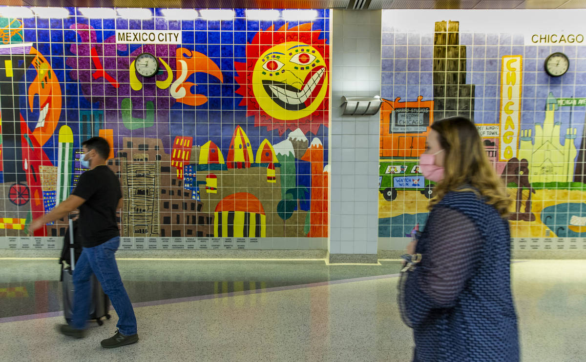 Passengers make their way to the Terminal 1 gates as COVID-19 safety precautions continue at Mc ...