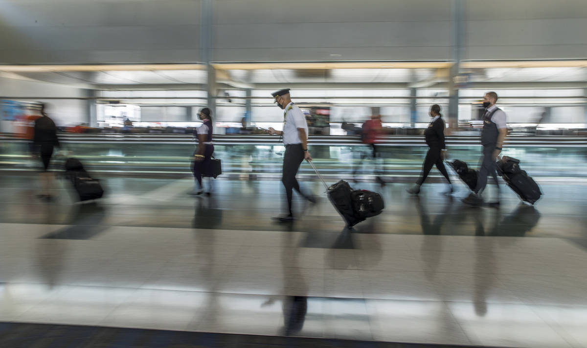 Pilots and passengers make their way through the Terminal 1 gates as COVID-19 safety precaution ...
