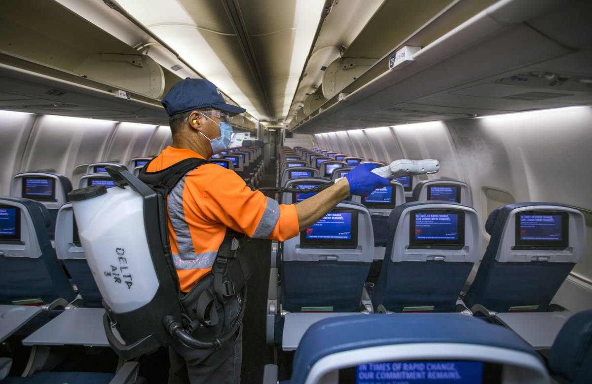 Delta Airlines employee Wansik Kim disinfects the interior of another airplane before departure ...