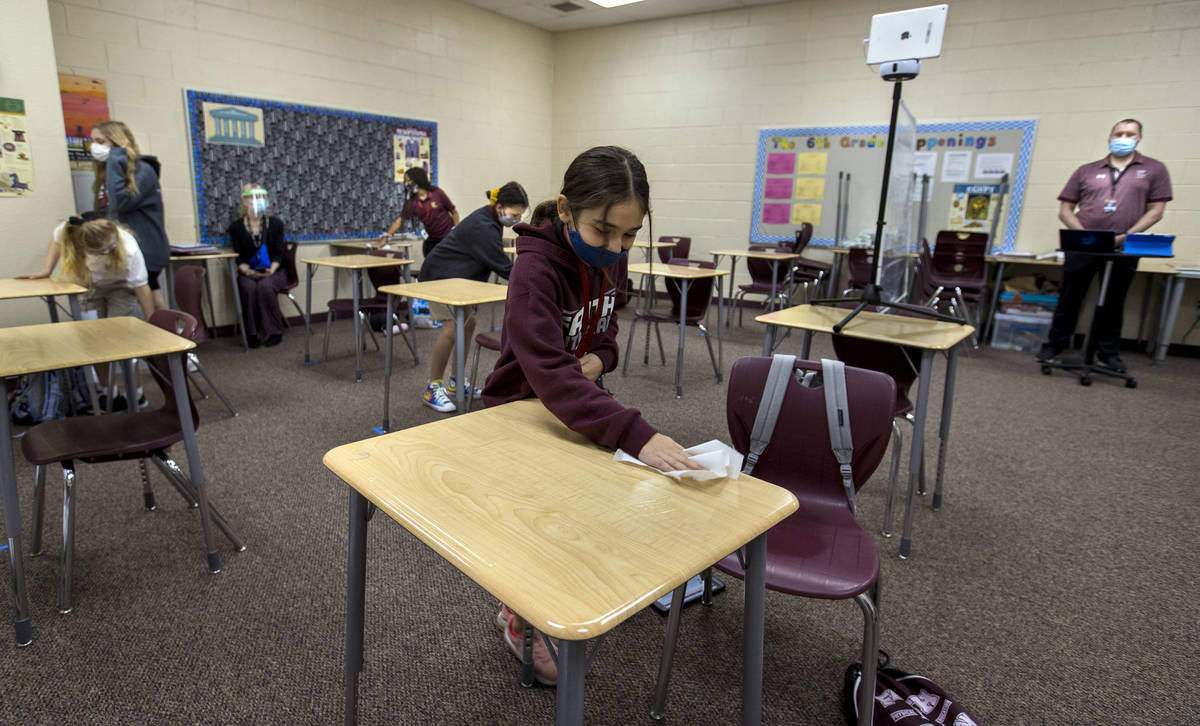 Student Alyssa Kazemi, 11, wipes down her desk with others in teacher Brandon Buskirk's 6th gra ...