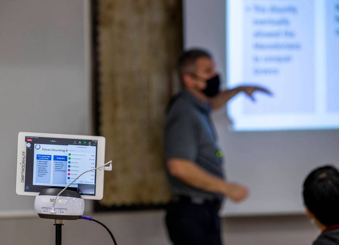 Teacher Joel Arnold is followed by Zoom projection on a swivel for remote students during his w ...
