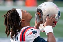 New England Patriots quarterback Cam Newton puts on his helmet before an NFL football game agai ...