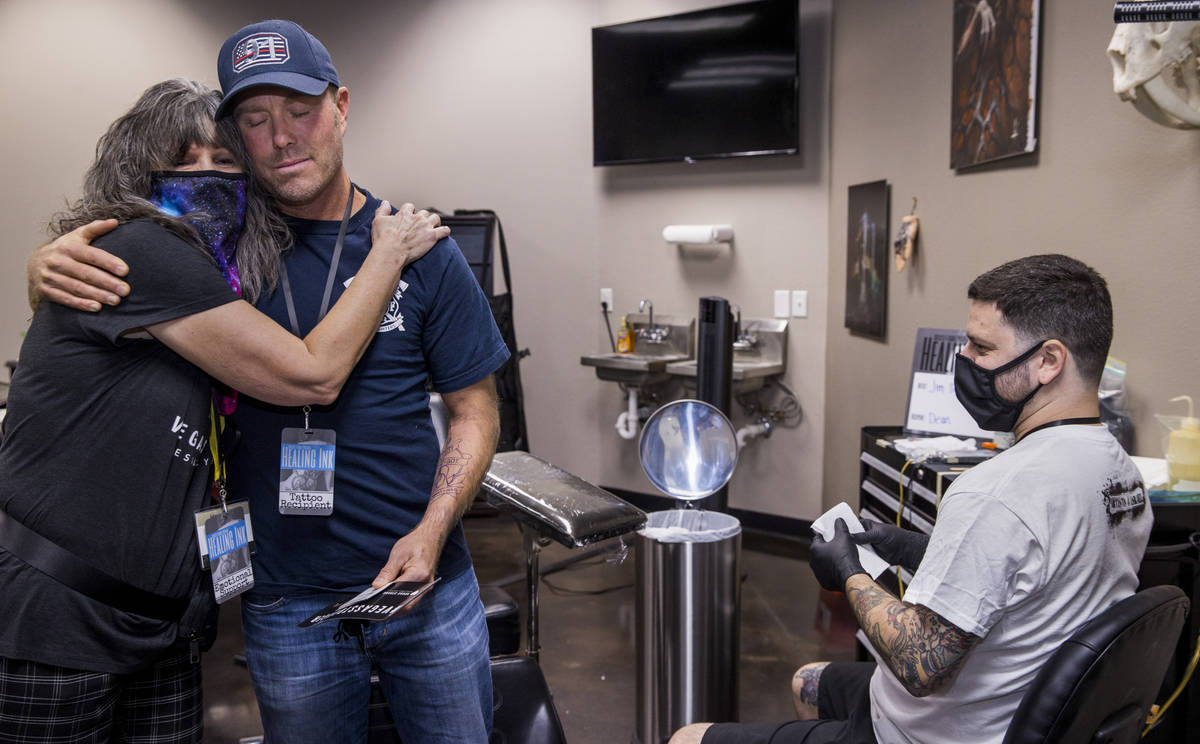 Terri Keener with the Vegas Strong Resiliency Center, left, hugs Dean McAuley with tattoo artis ...