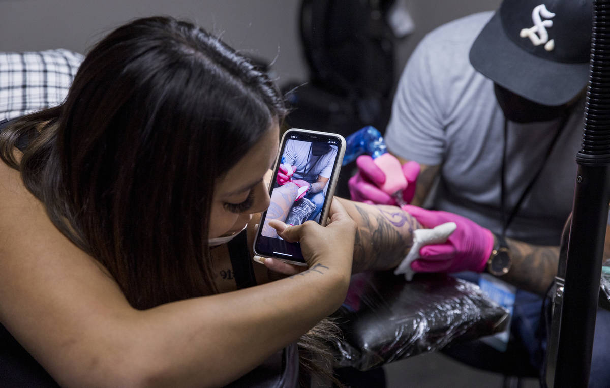 Natalia Baca, left, grabs a shot of her tattoo artist Sam Chacon as Route 91 shooting survivors ...