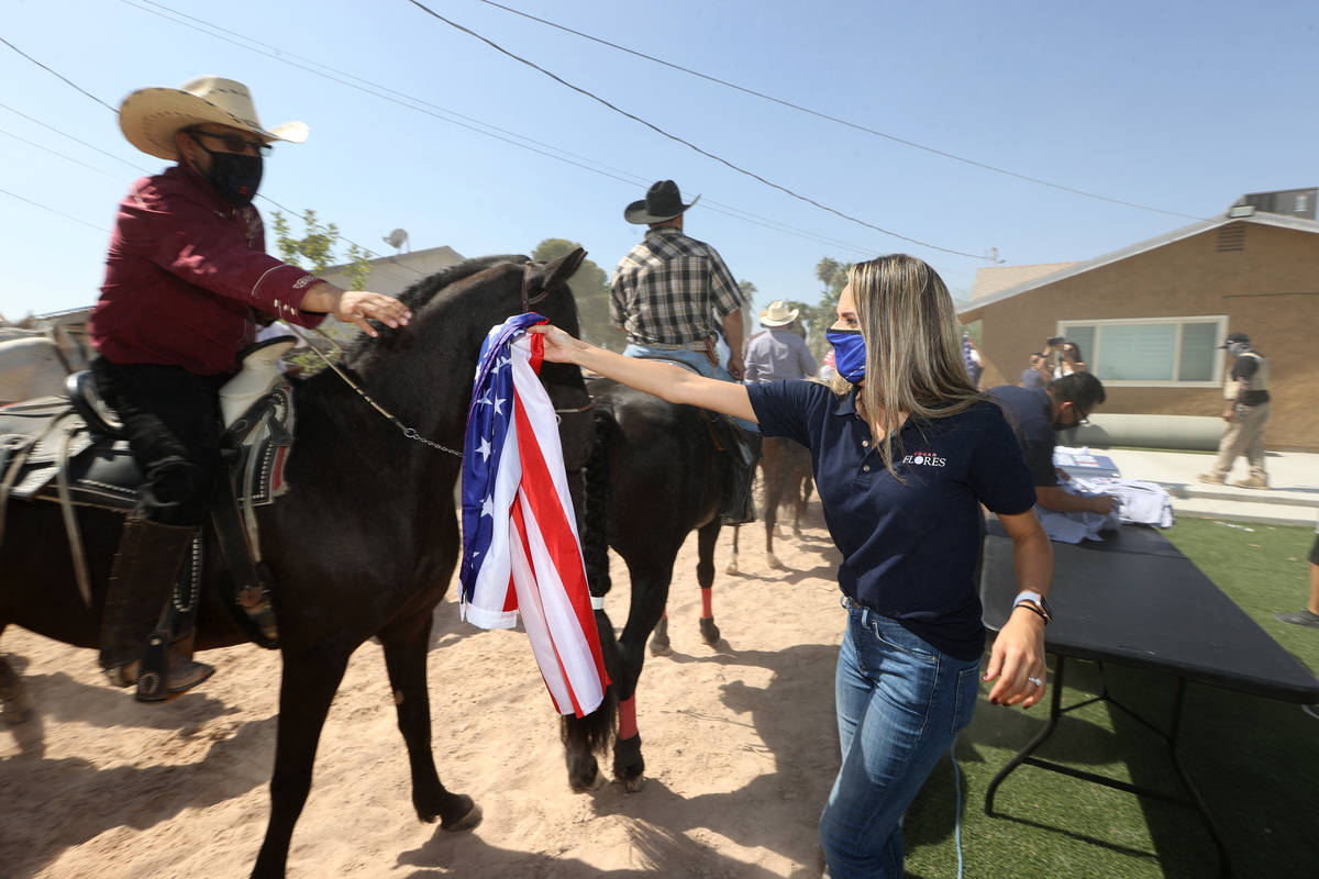 Karen Montiel hands out an American flag to a horseback rider in preparation to a canvassing ev ...