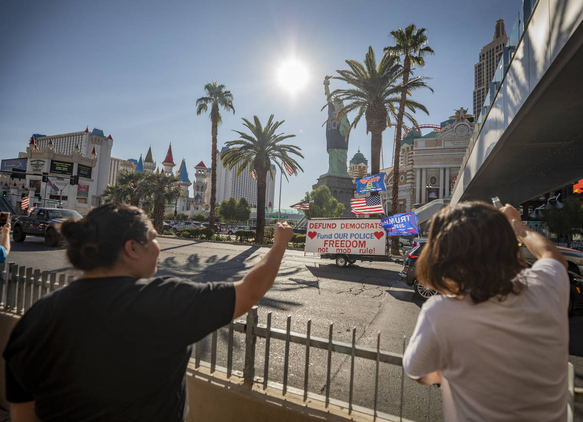 Individuals yell in disagreement as a caravan of Trump supporters ride down the Las Vegas Strip ...