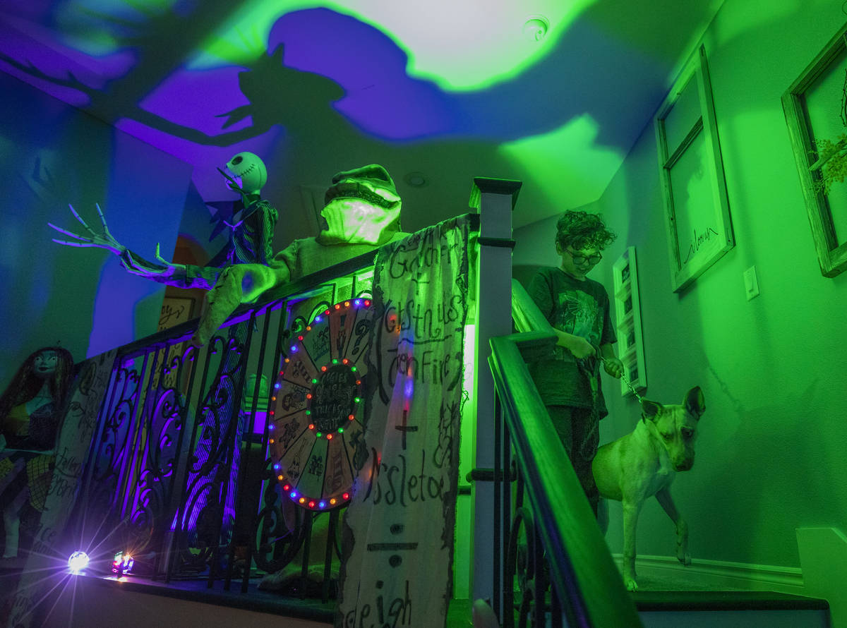Evan Garcia, 10, walks his dog Jessie down the stairs of their Disney Halloween-themed home in ...