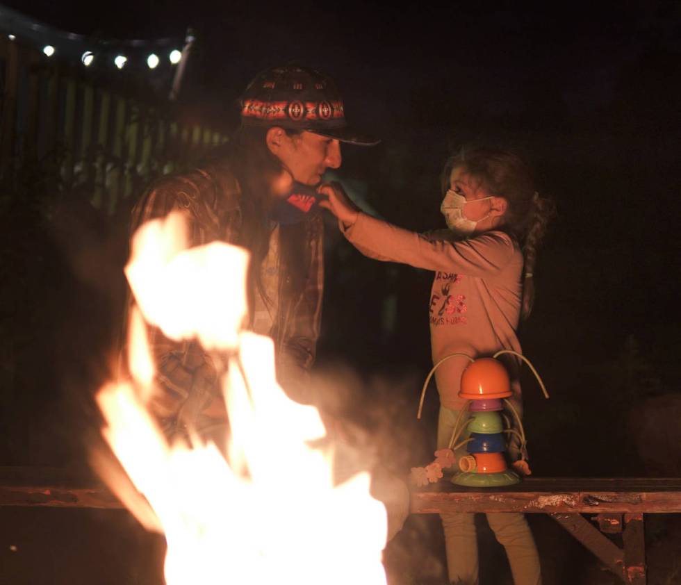 Zonnie Benally instructs her father, Clayson, to put on his mask as the two enjoy a campfire on ...