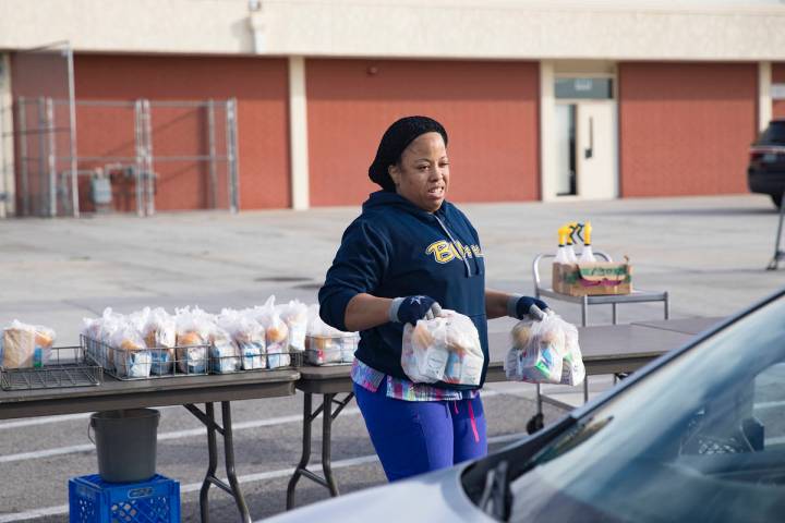 A Clark County School District employee hands out breakfast and lunch packages to families at C ...