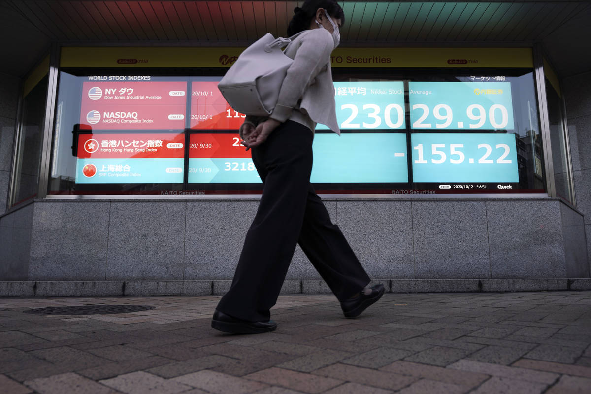 A woman walks past an electronic stock board showing Japan's Nikkei 225 index at a securities f ...