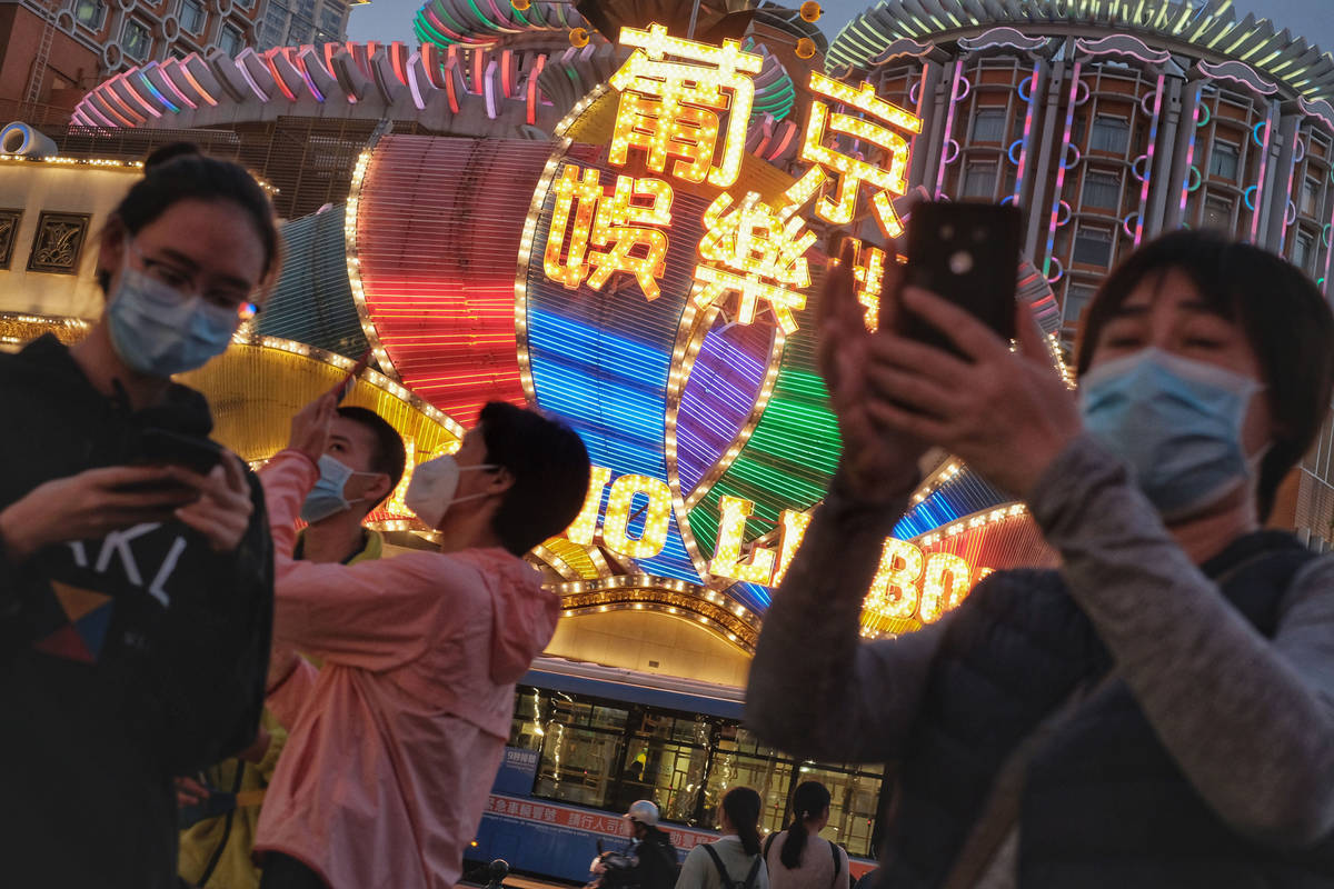 Tourists wearing masks take photographs outside the Casino Lisboa in Macao, China, in January 2 ...