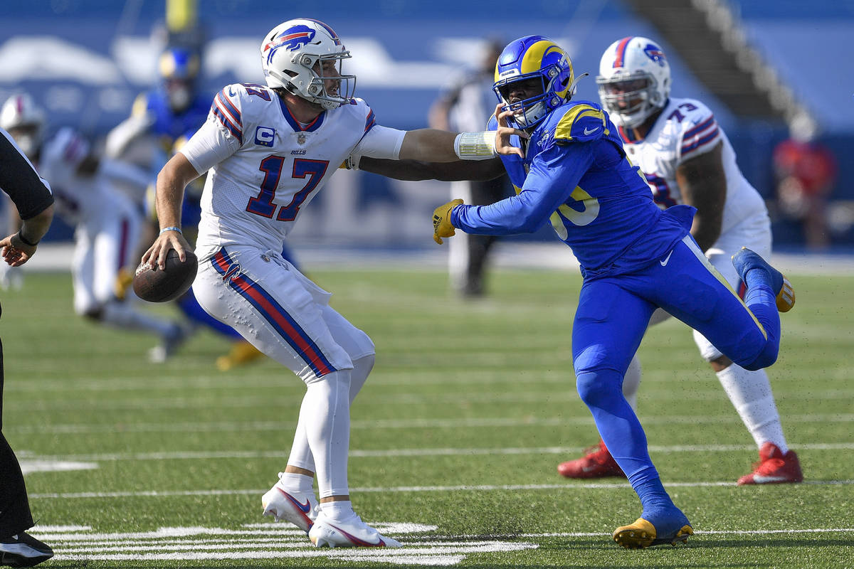 Buffalo Bills quarterback Josh Allen, left, tries to avoid pressure by Los Angeles Rams linebac ...