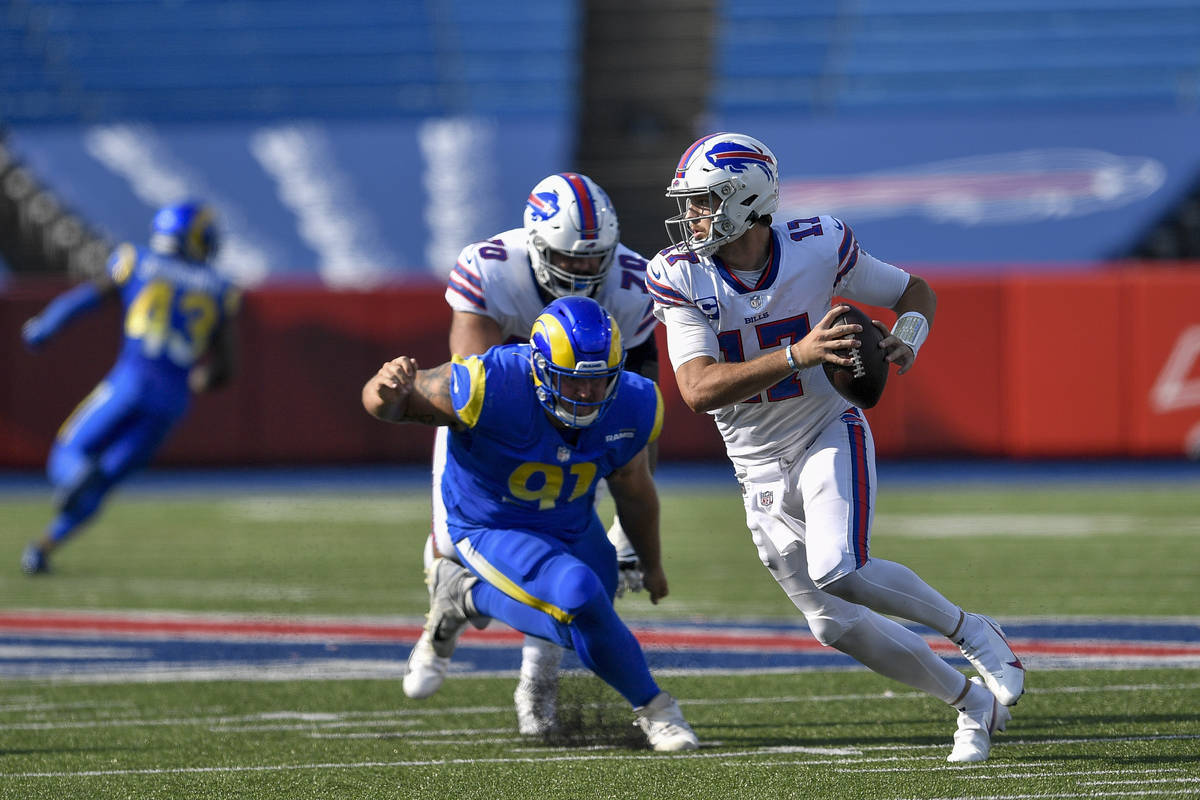 Buffalo Bills quarterback Josh Allen, right, tries to avoid pressure by Los Angeles Rams defens ...