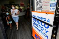 A woman leaves a store offering services to send remittances to Mexico and Central America, Fri ...