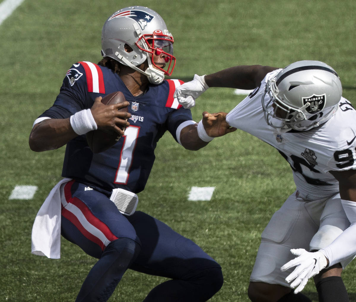New England Patriots quarterback Cam Newton (1) stiff arms Las Vegas Raiders defensive end Clel ...