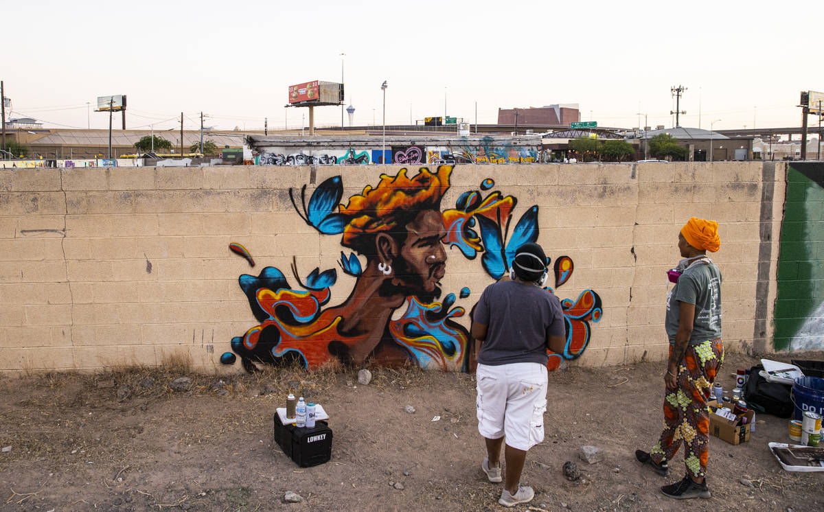 Artist Sloane Siobhan, of Las Vegas, looks at her mural "Butterfly Boy" alongside wif ...