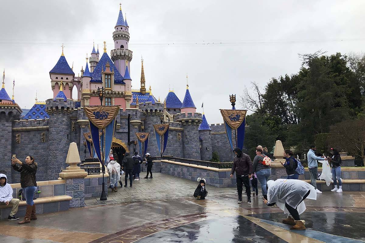 FILE - In this March 13, 2020 file photo, visitors take photos at Disneyland in Anaheim, Calif. ...
