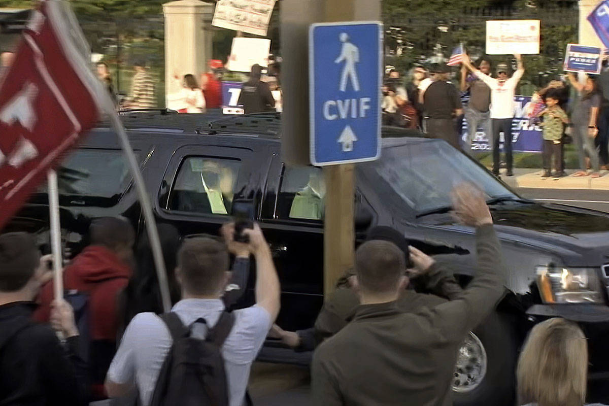 In this image from video, President Donald Trump waves as he drives past supporters gathered ou ...