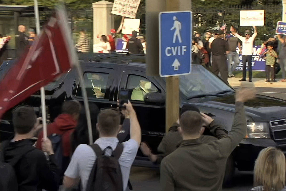 In this image from video, President Donald Trump waves as he drives past supporters gathered ou ...