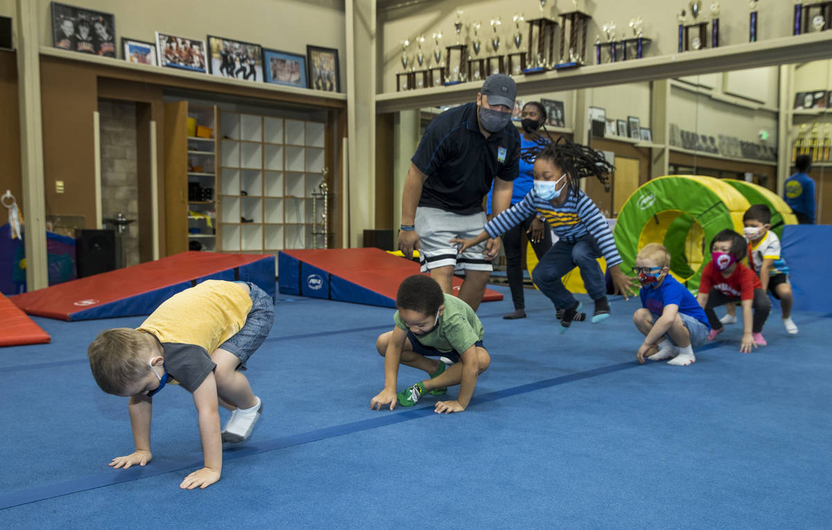 Instructor Mo Bonnet, center, encourages kindergarteners in frog jumps while exercising during ...
