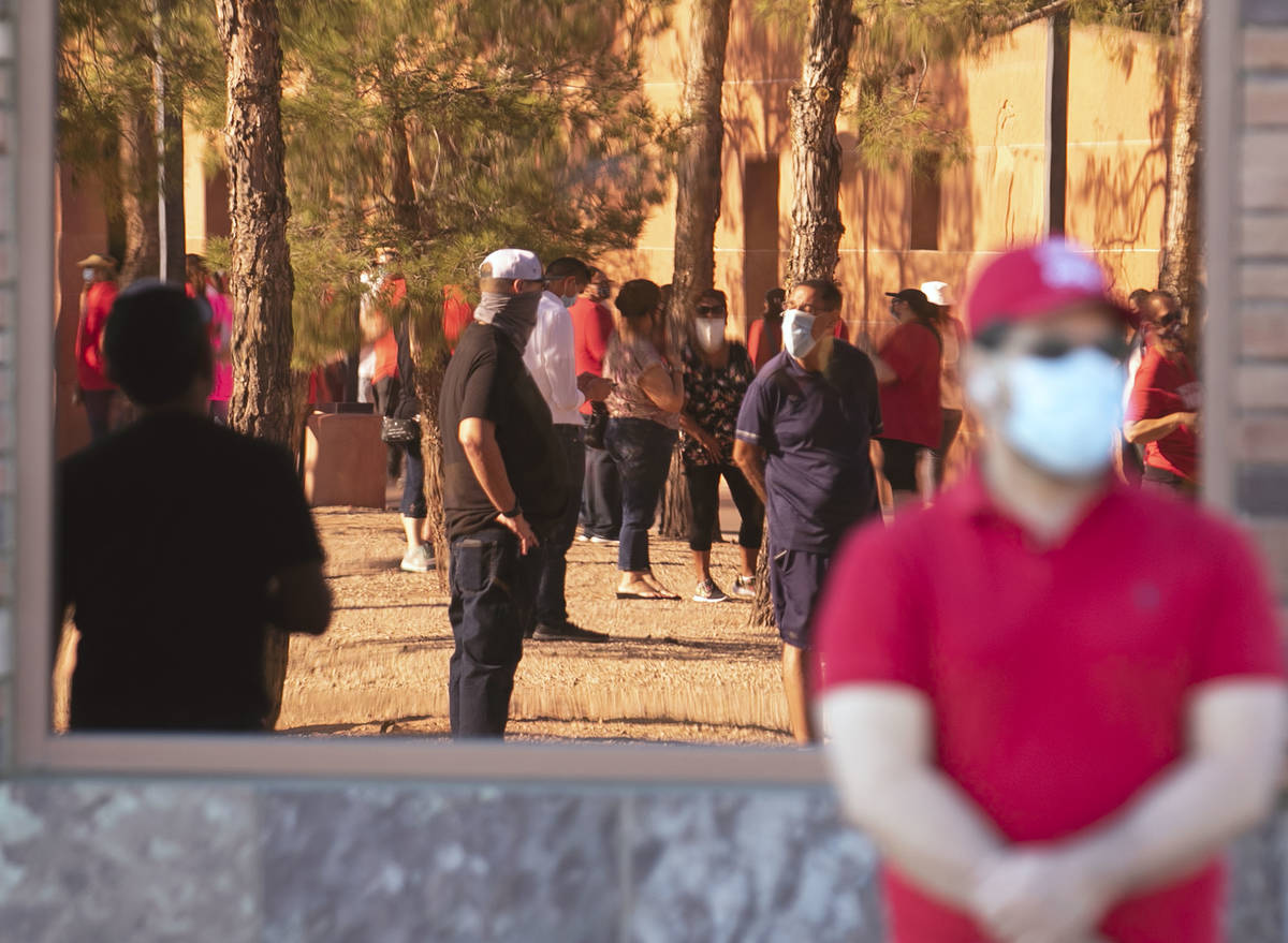 Workers are reflected in window as they rally outside of the Clark County Commission Building o ...