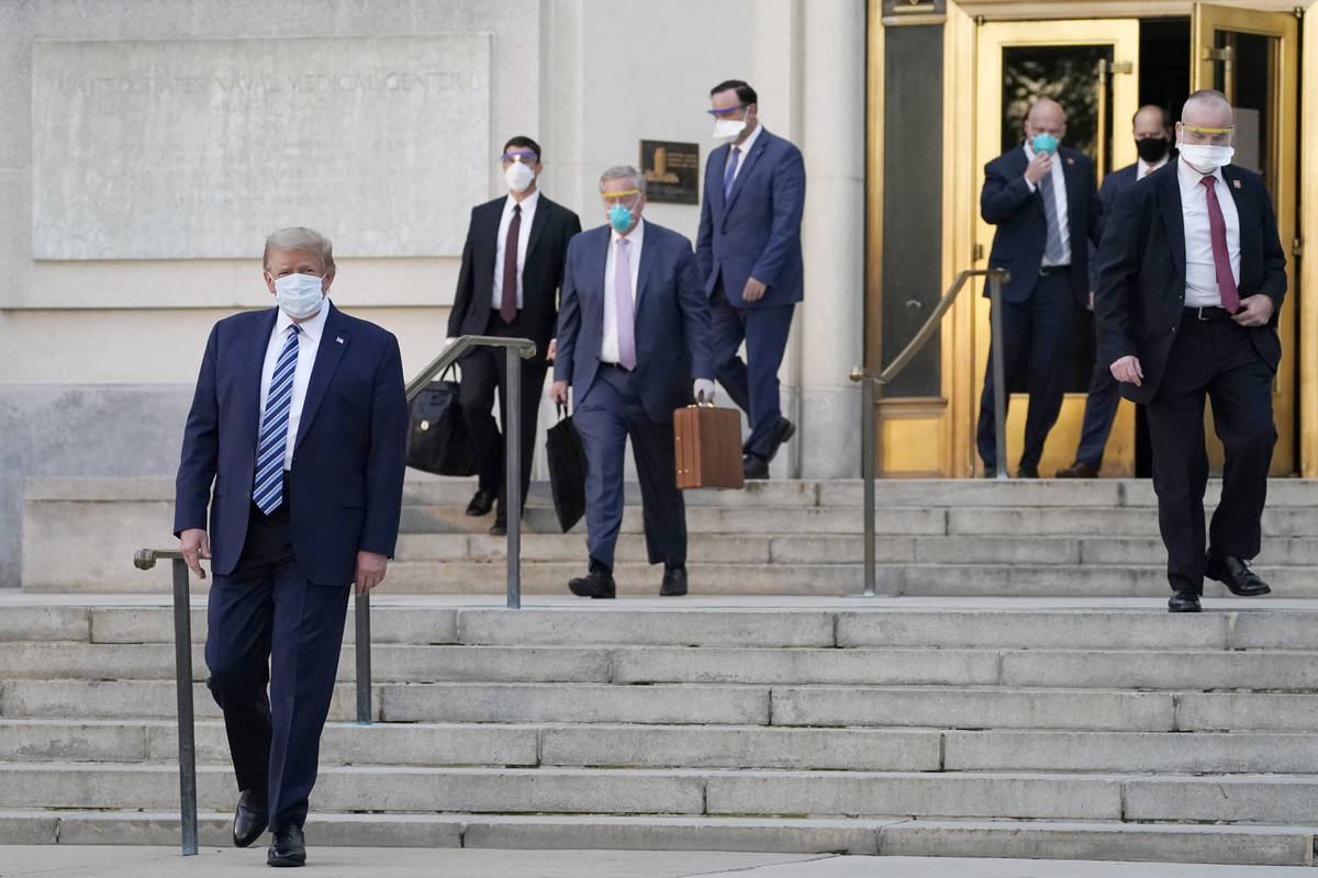 President Donald Trump, left, walks out of Walter Reed National Military Medical Center to retu ...