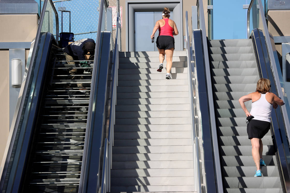 A worker performs scheduled maintenance on an escalator for the pedestrian bridge between Excal ...
