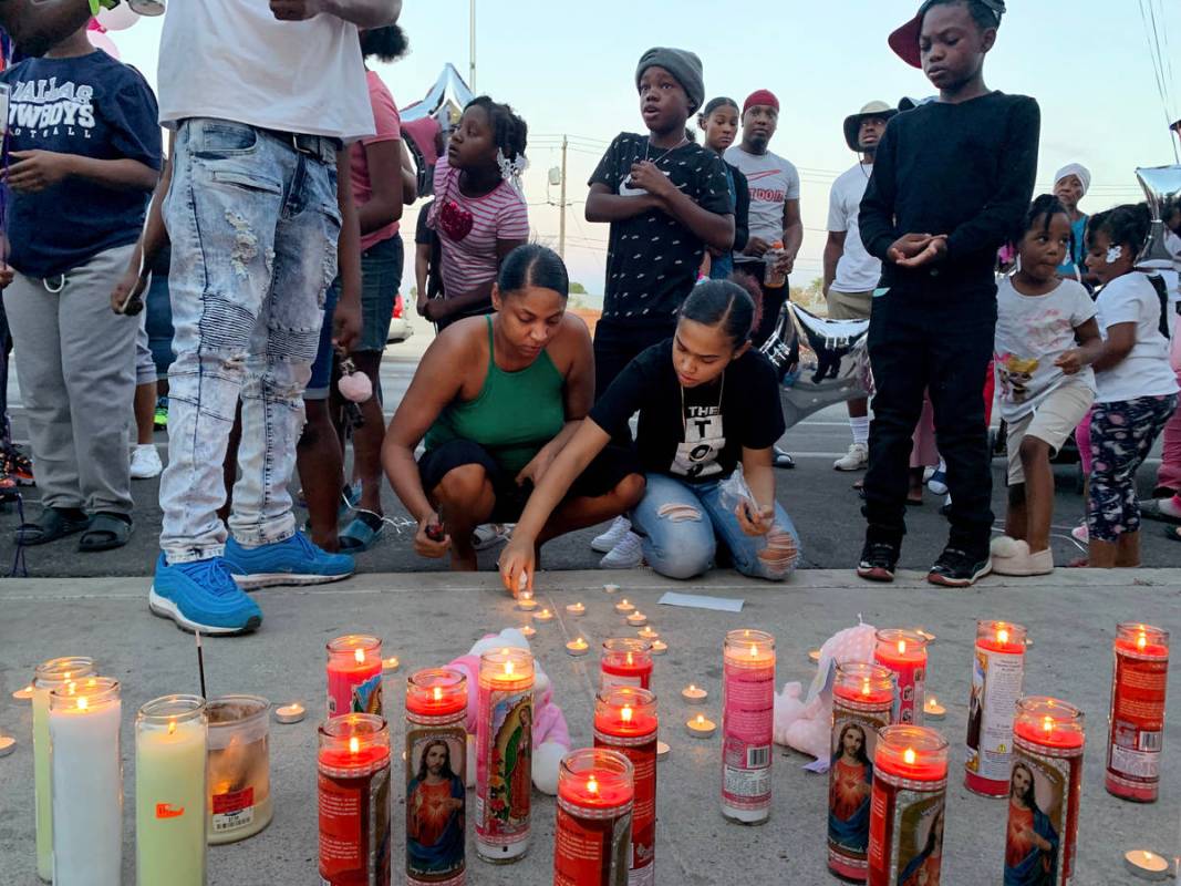Aunts of 1-year, 9-month-old Sayah Deal, Katie Porter, left, and Christina Scott, light candles ...