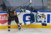 Vegas Golden Knights' Chandler Stephenson (20) checks Vancouver Canucks' Christopher Tanev (8) ...