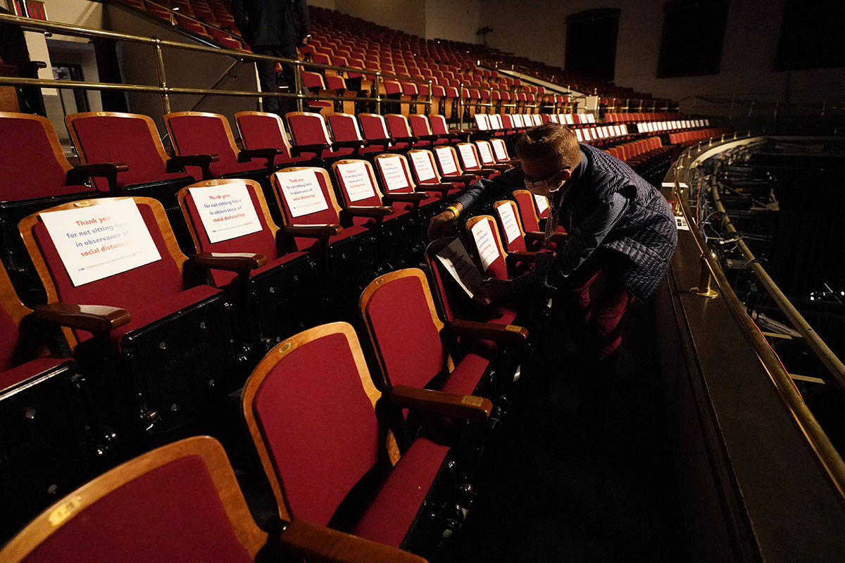 A member of the production staff puts labels on seats in an effort to keep seats socially dista ...