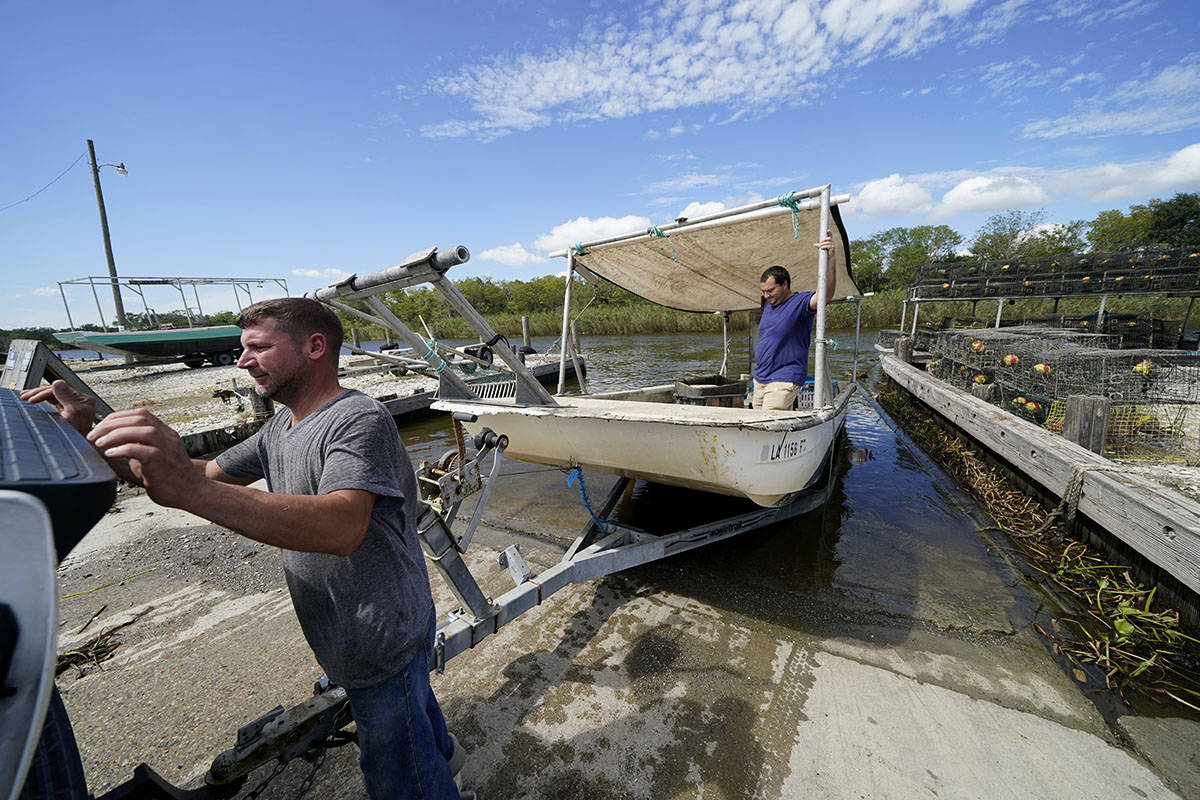 Charles Russ and Allan Bergeron, right, pull their boat from the water after pulling their crab ...