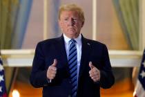 President Donald Trump stands on the balcony outside of the Blue Room as returns to the White H ...