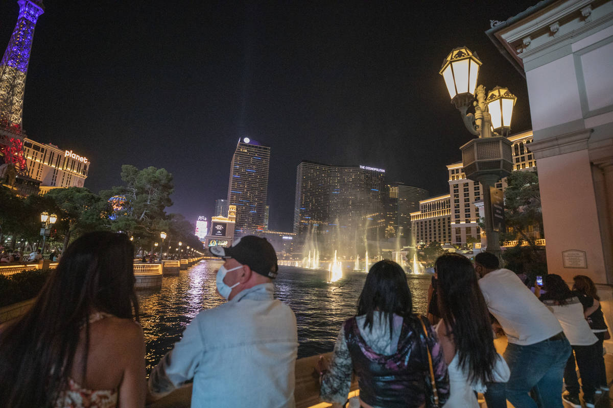 Tourists watch the Bellagio hotel and casino fountains, late Friday night on Oct. 7, 2020. (Eli ...