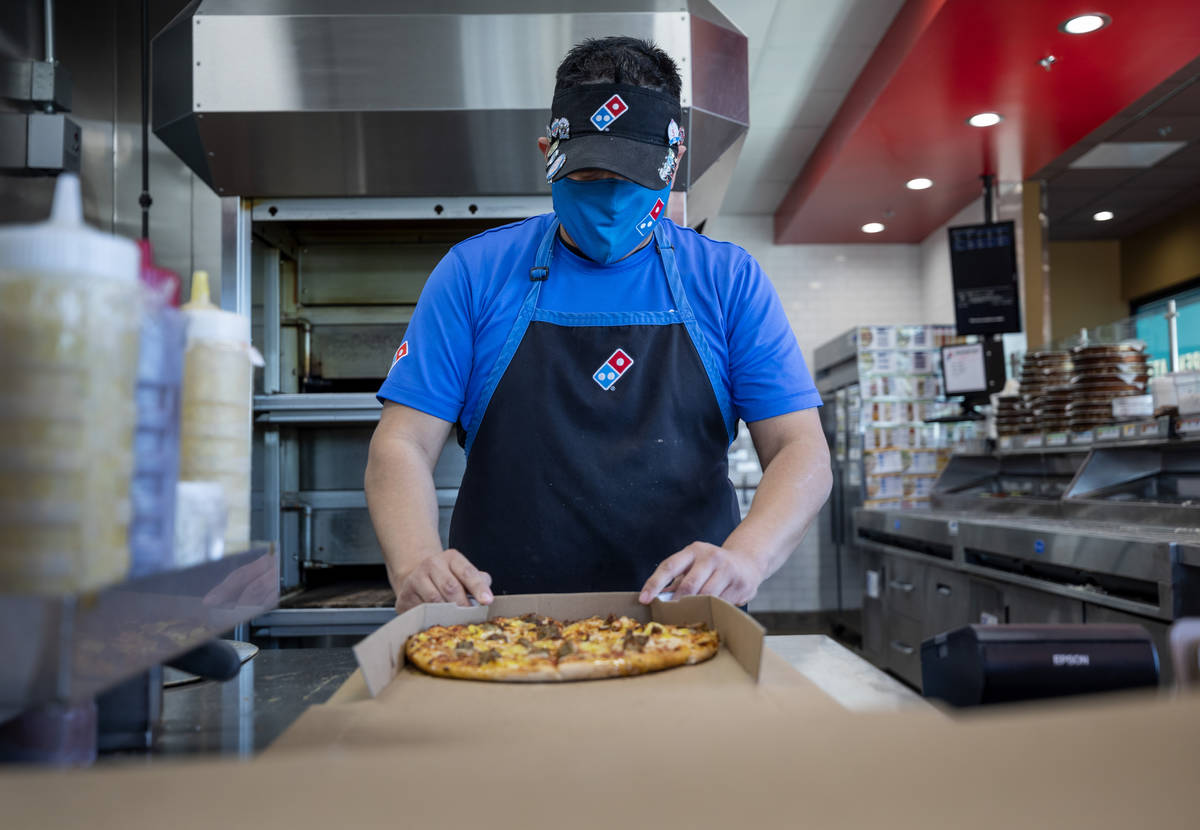 Domino's general manager Jessy Cortez boxes a pizza to be delivered at the Domino's located off ...
