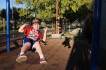 Joshua Farren, 7, with his father Anthony watching, swings at the Centennial Hills Park playgro ...