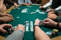 A poker player checks his cards during the World Series of Poker on Monday, June 26, 2017, at t ...