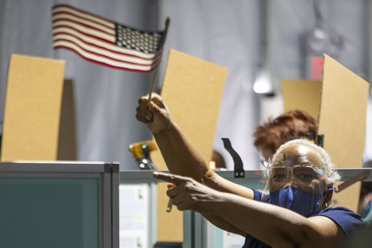 Poll worker Tamara Nash guides voters to empty spaces with an American flag at the Boulevard Ma ...