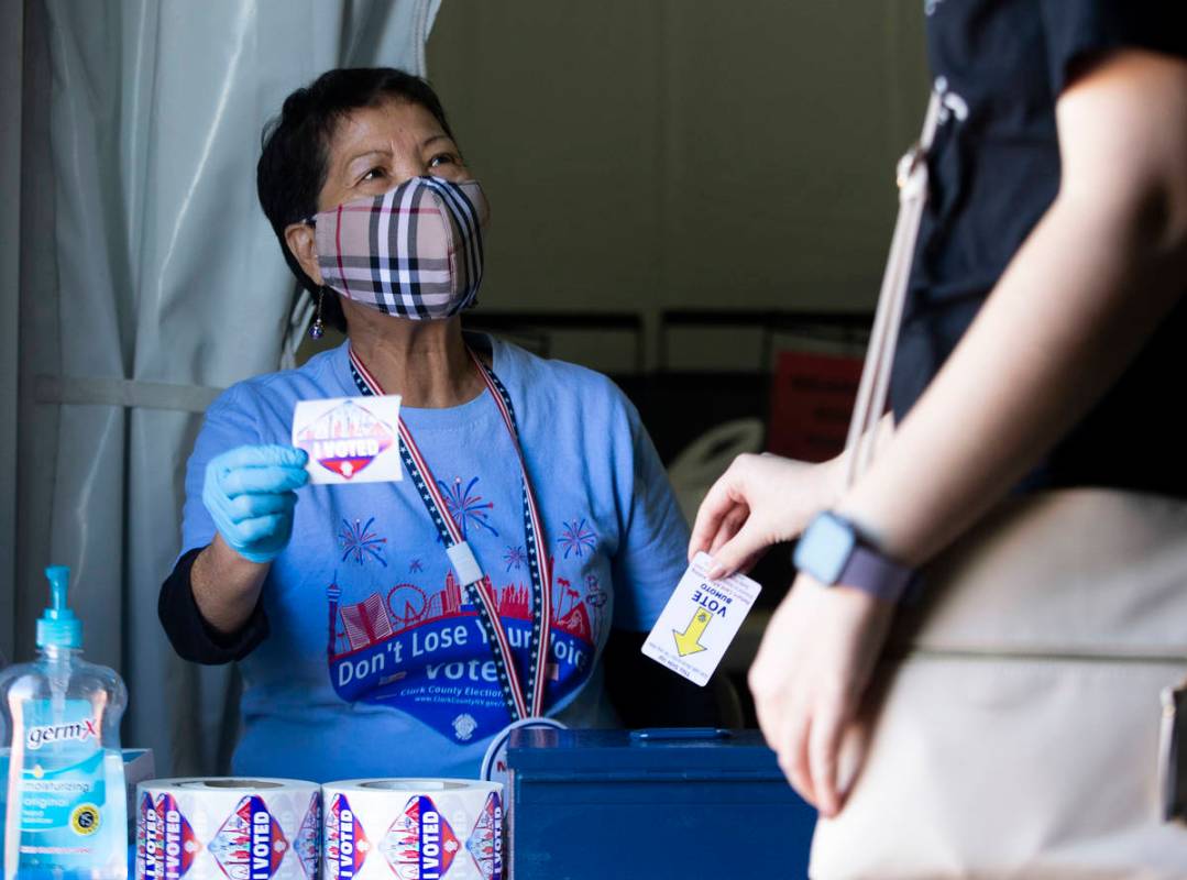 Wilma Dal Mundo, who has been a poll worker for 13 years, hands out "I Voted" sticker ...
